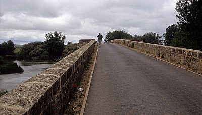 Jakobsweg (Camino Francés): Ein Pilger überquert die Brücke über den Río Pisuerga - Castilla y León