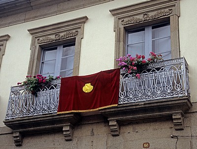 Jakobsweg (Camino Francés): Wandteppich mit Jakobsmuschel zwischen zwei Balkonen - Sarria