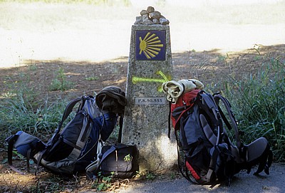 Jakobsweg (Caminho Português): Zwischen San Mauro und Tivo – Rucksäcke neben einem Camino-Wegstein  - Galicia
