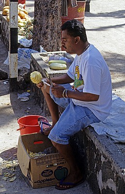 Ananasverkäufer beim Schälen einer Ananas - Pereybere